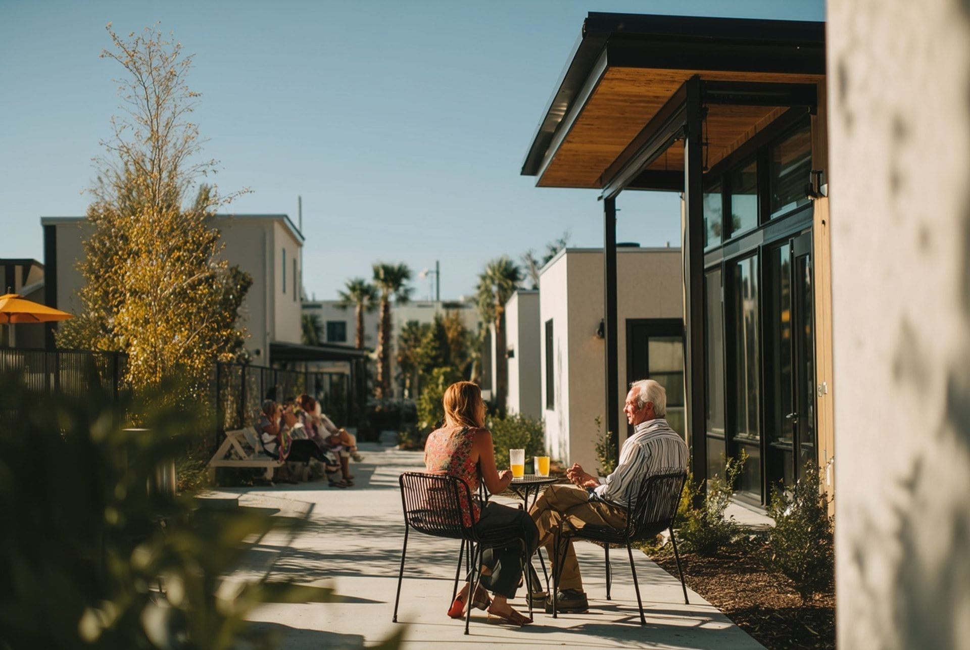 Residents seated at a courtyard table between VeraFrame homes